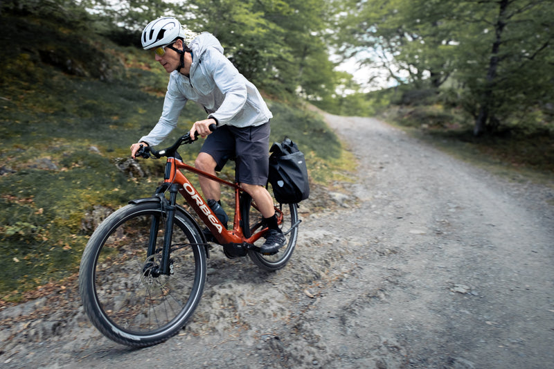 Maður hjólar eftir malarstíg á rauðu Orbea Kemen Adv rafmagnsborgarhjóli