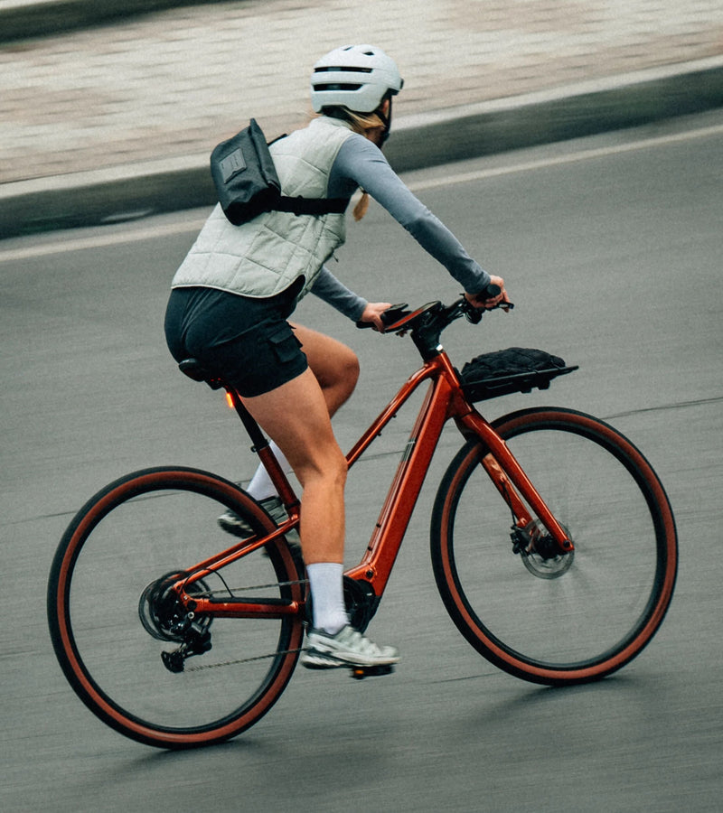 Kona brunar um á rauðu flottu Orbea Carpe rafmagnsborgarhjóli