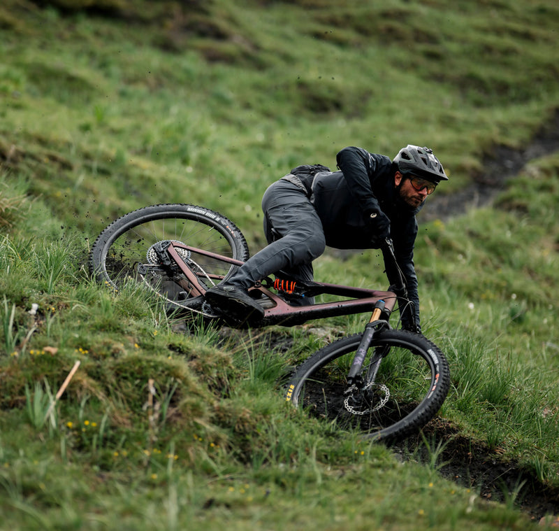 Maður brunar niður hlykkjótta fjallshlíð á fjólubláu Orbea Occam LT fjallahjóli 