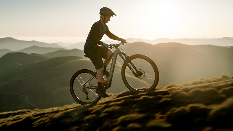 Maður hjólar upp fjall á silfurlituðu Orbea Urrun hardtail rafmagnsfjallahjóli