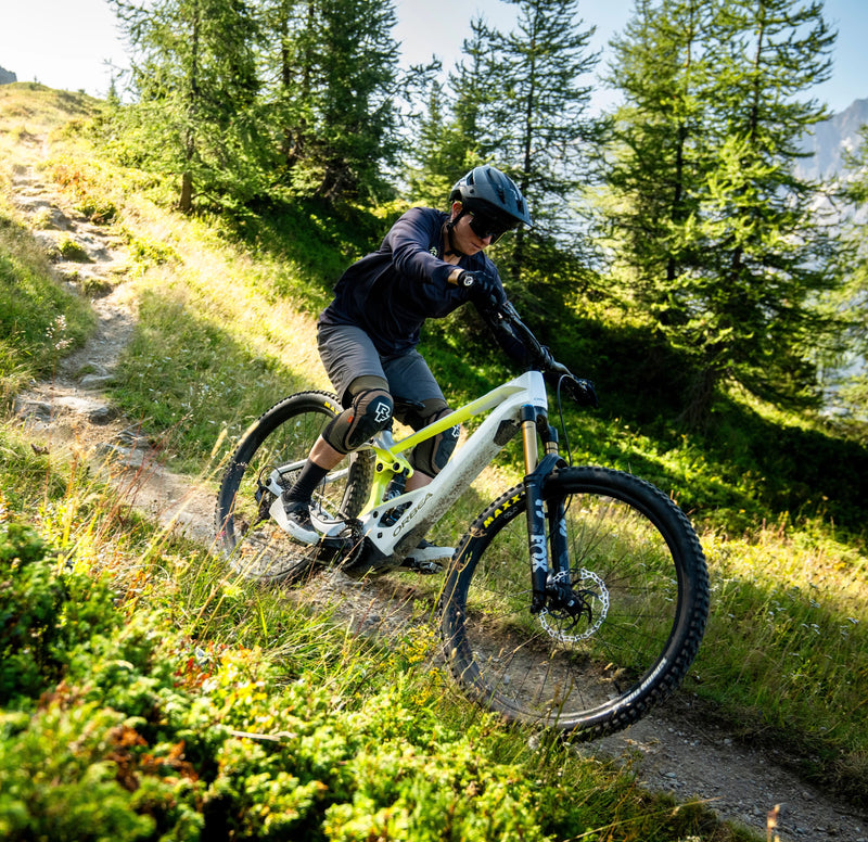 Kona brunar niður fjallshlíð á hvítu og gulu Orbea Wild Enduro rafmagnsfjallahjóli