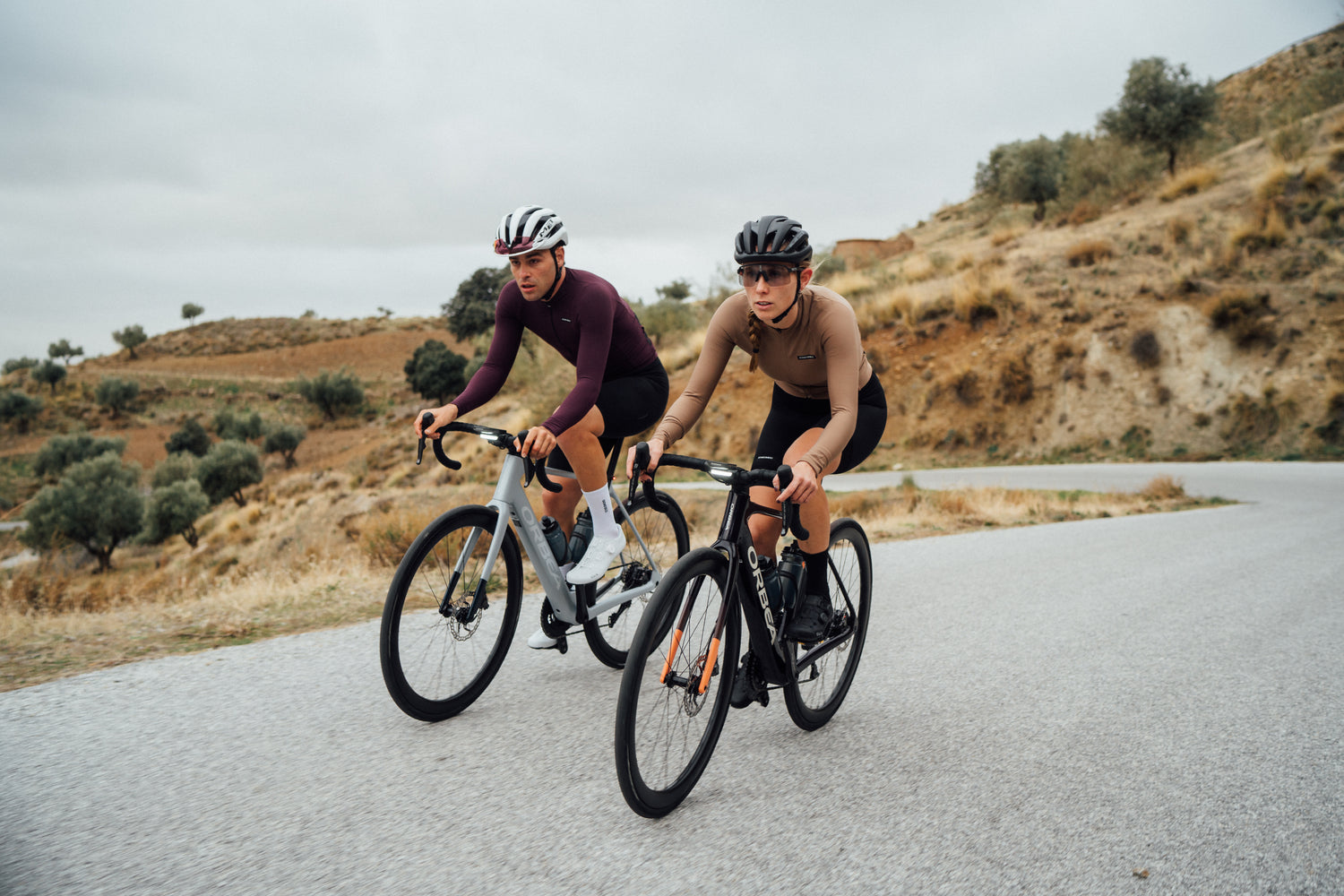 Tvö Orbea Gain rafmagnsgötuhjól bruna upp klifur, bæði hjólin eru með ljósin á